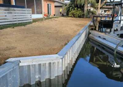 Aluminum seawall and cap along a canal beside a graded backyard