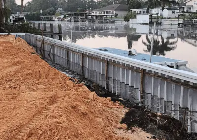 New aluminum seawall with fresh fill sand along a canal