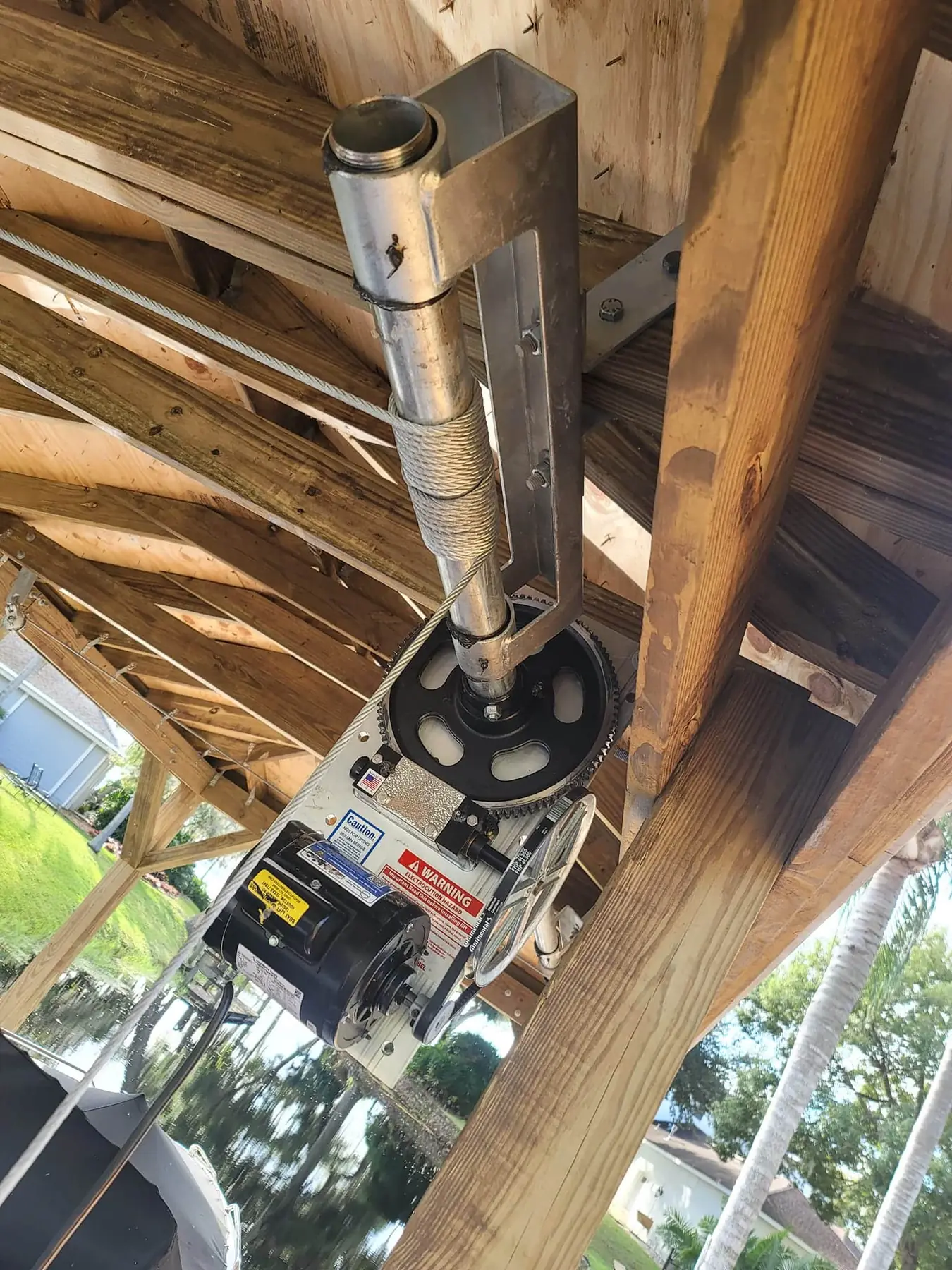 Boat lift motor, gear and cable winch mounted under a boathouse roof
