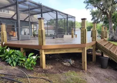 New composite deck with wooden posts, cable railing and stairs beside a pool enclosure