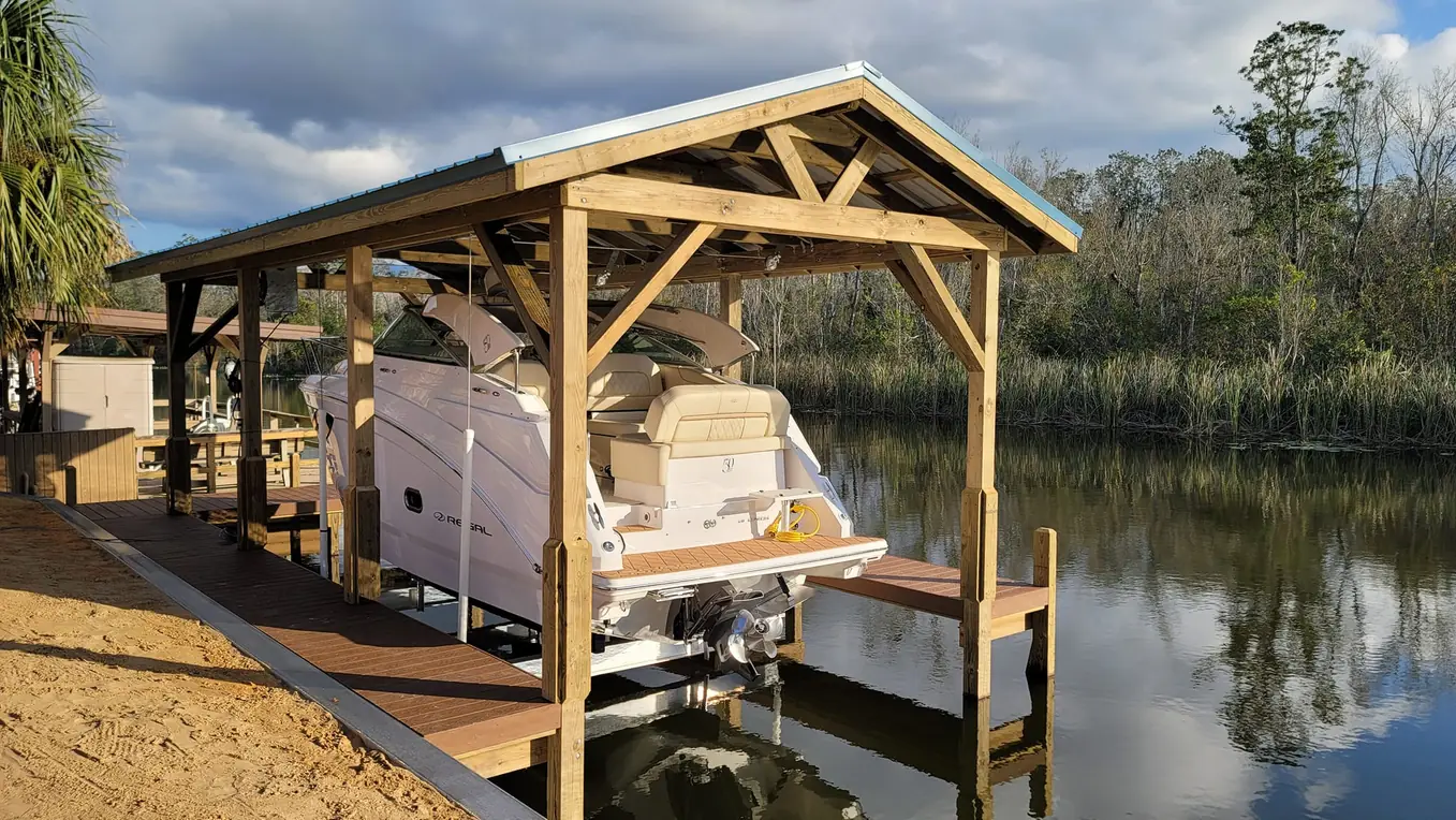 Covered boat lift with a cruiser raised above the water under a wooden roof