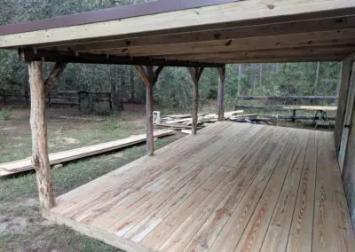 Covered wooden deck with rustic log posts in a wooded yard