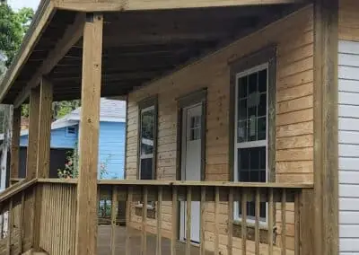 Covered wooden front porch with railing on a newly built wood-sided home