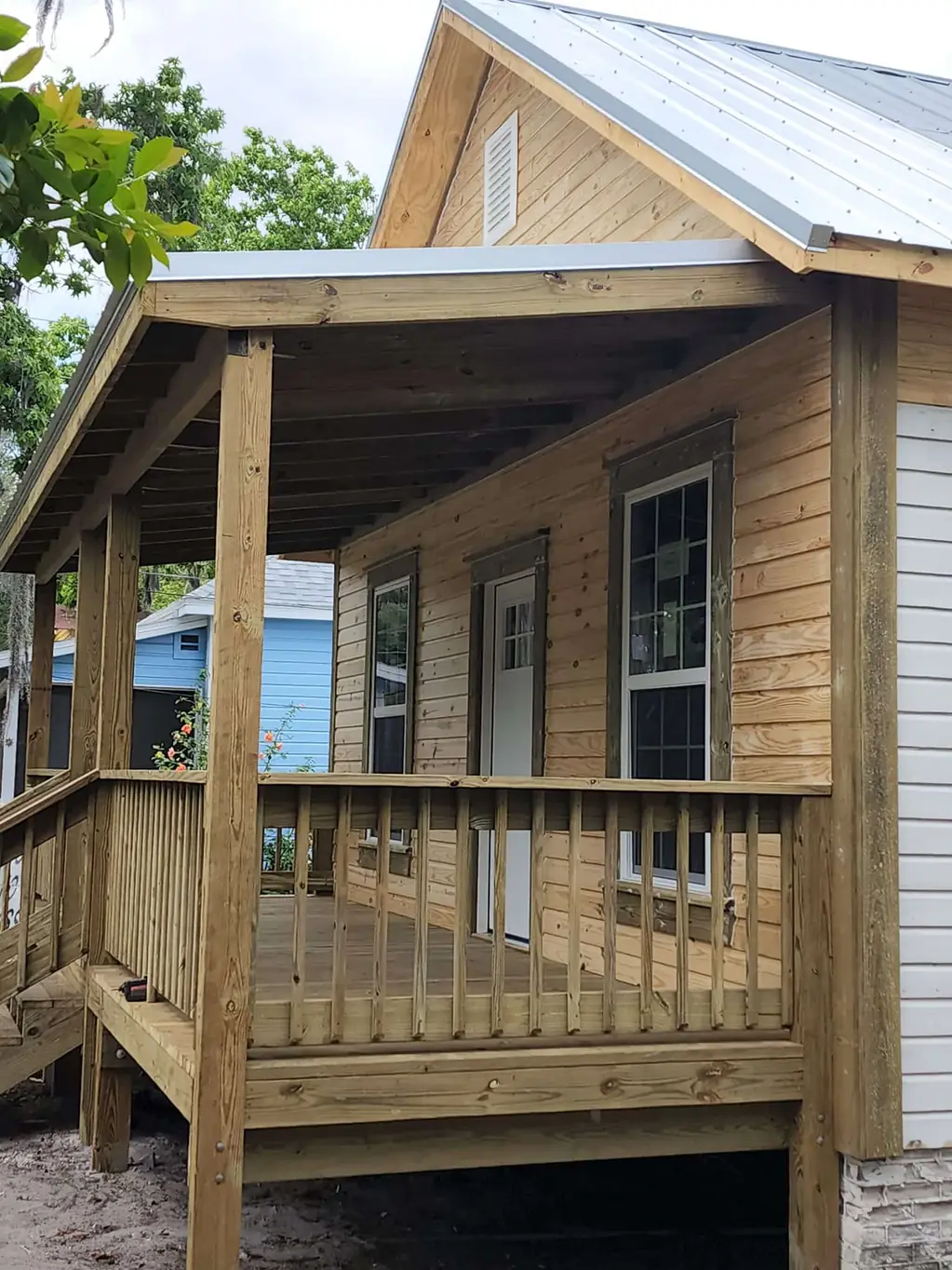 Covered wooden front porch with railing on a newly built wood-sided home