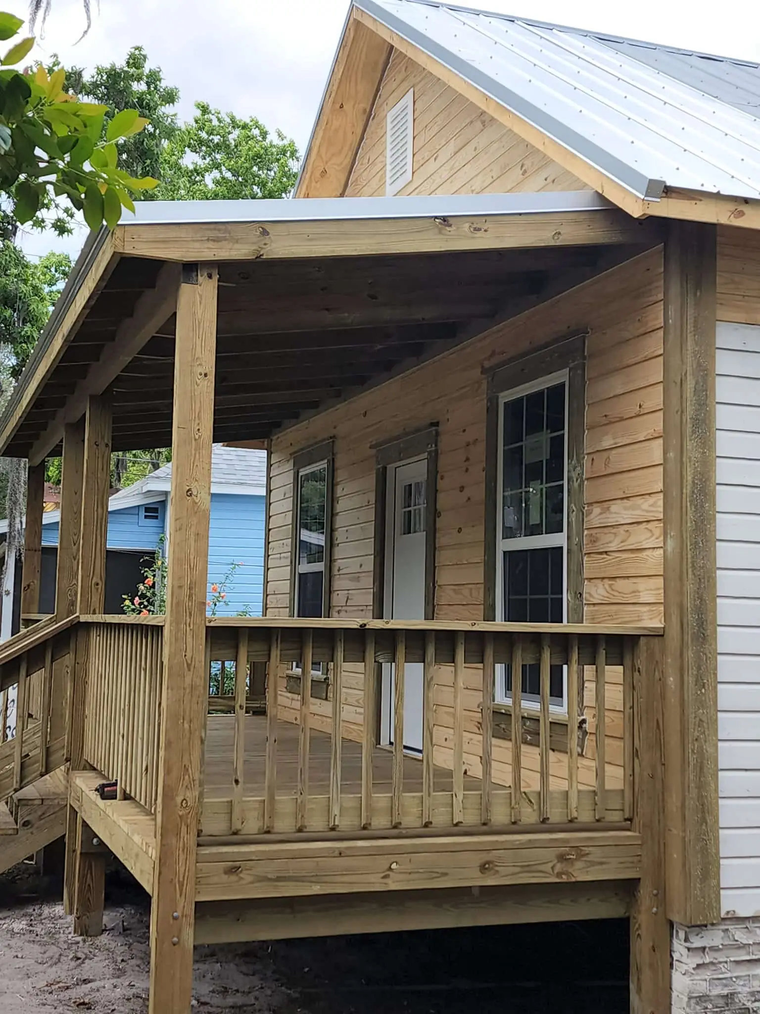 Covered wooden front porch with railing on a newly built wood-sided home