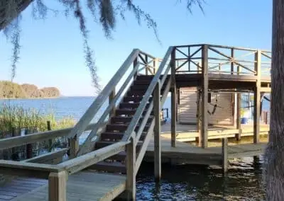 Wooden dock with stairs to a two-story boathouse sundeck on a lake