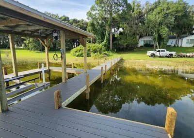 Long gray composite dock with a covered slip extending into a lake