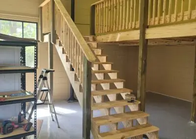 Interior wooden staircase leading to a railed loft in a workshop building