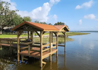 Two-roof covered dock with a red metal roof over a calm lake