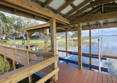 Inside a covered boathouse with a boat lift and wooden walkway on a lake