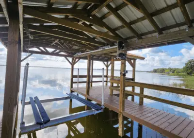 Covered boat slip with an empty lift cradle and composite decking on a lake