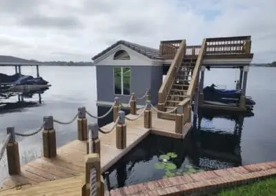 Rope-railed dock leading to a boathouse with stairs to a rooftop deck