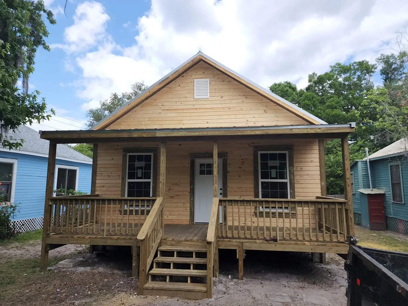 New wood-sided cottage with a covered front porch, railing and steps