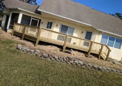 Long wooden deck with railing along the back of a house