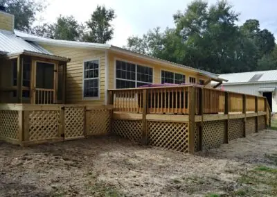 Wraparound wooden deck with lattice skirting and a screened porch on a yellow house