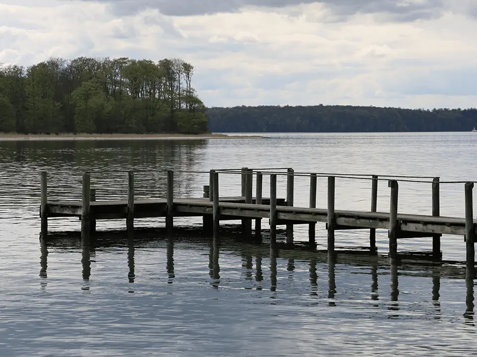 Weathered wooden dock with a rope railing over a calm lake